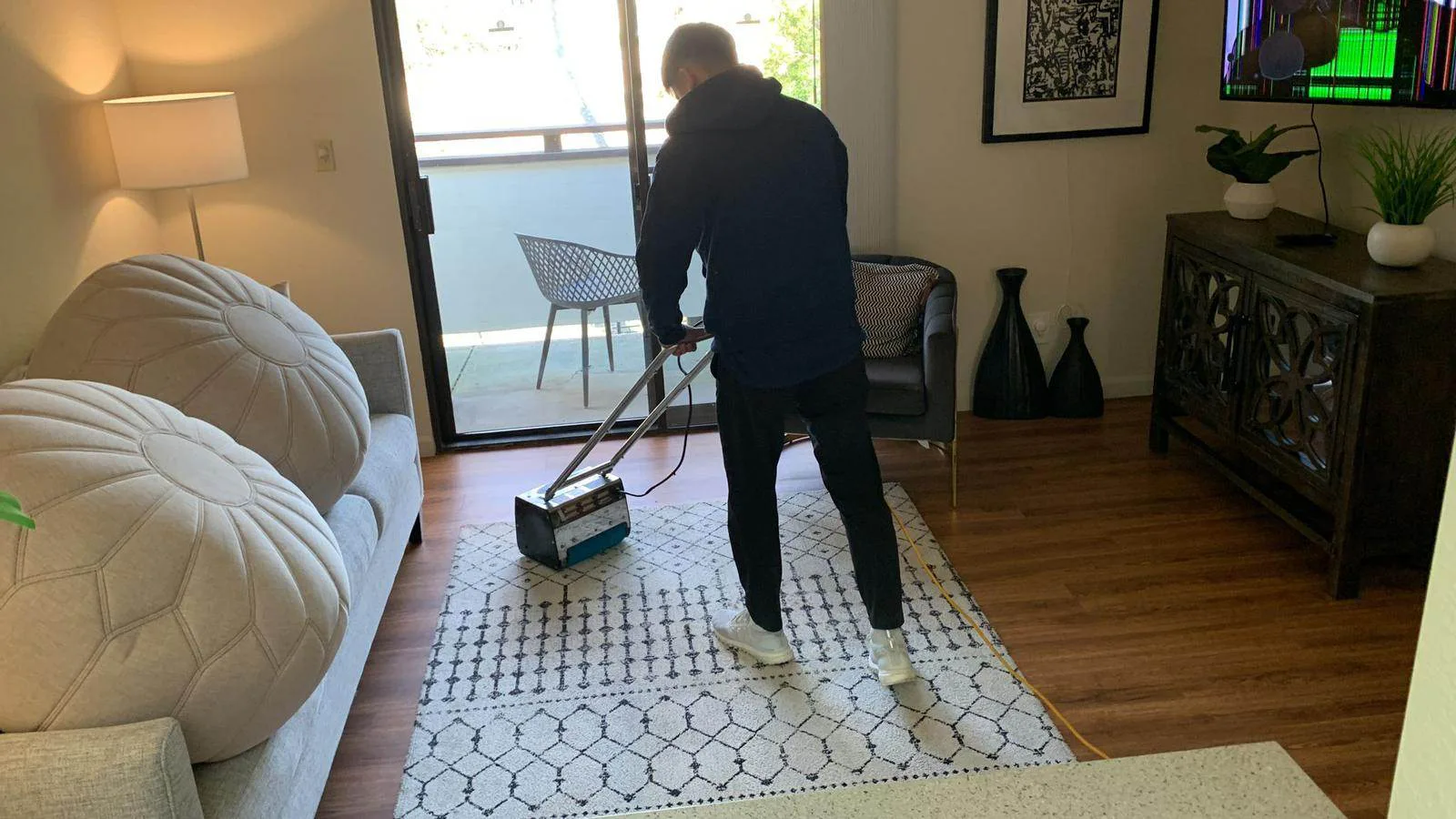 Master Clean technician operating a rotary carpet cleaning machine on a patterned area rug in a bright living room.
