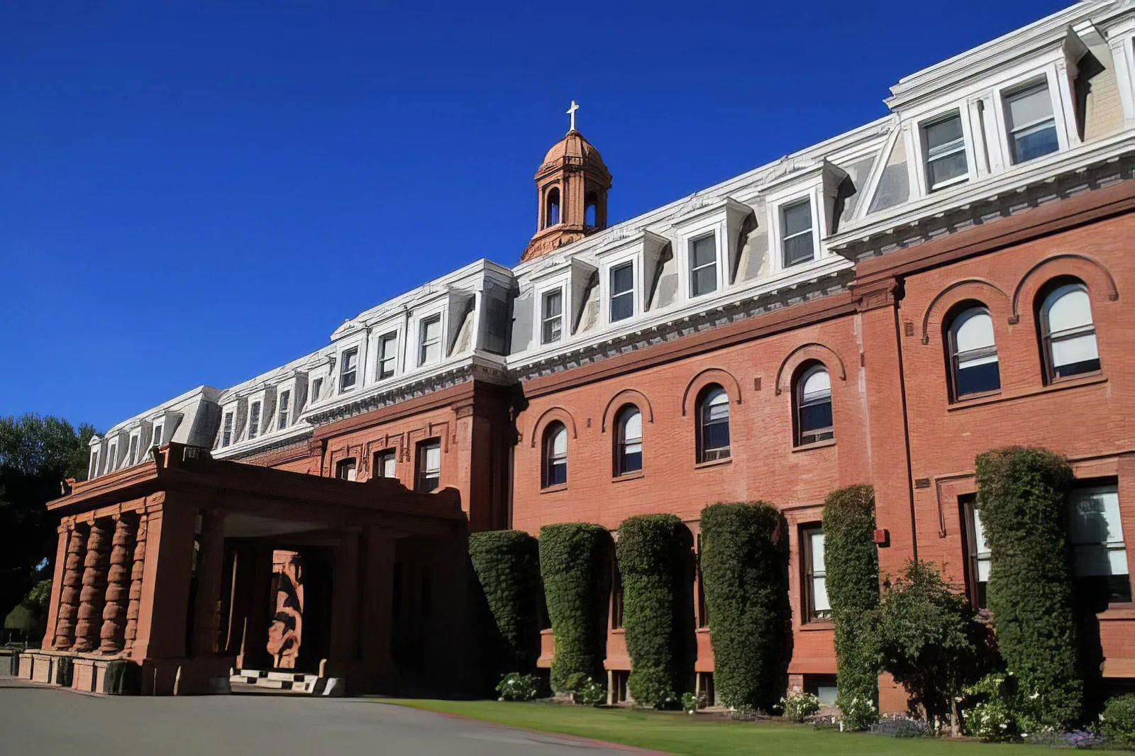Historic red-brick mission-style building with bell tower under blue sky