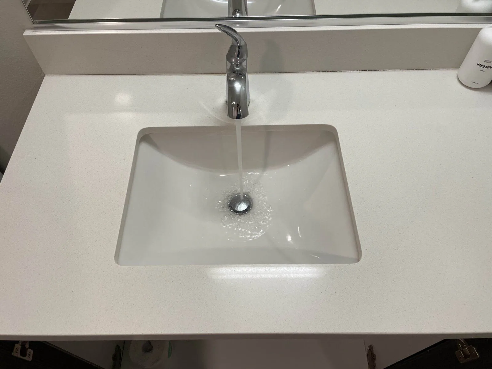Clean white bathroom sink with faucet water running