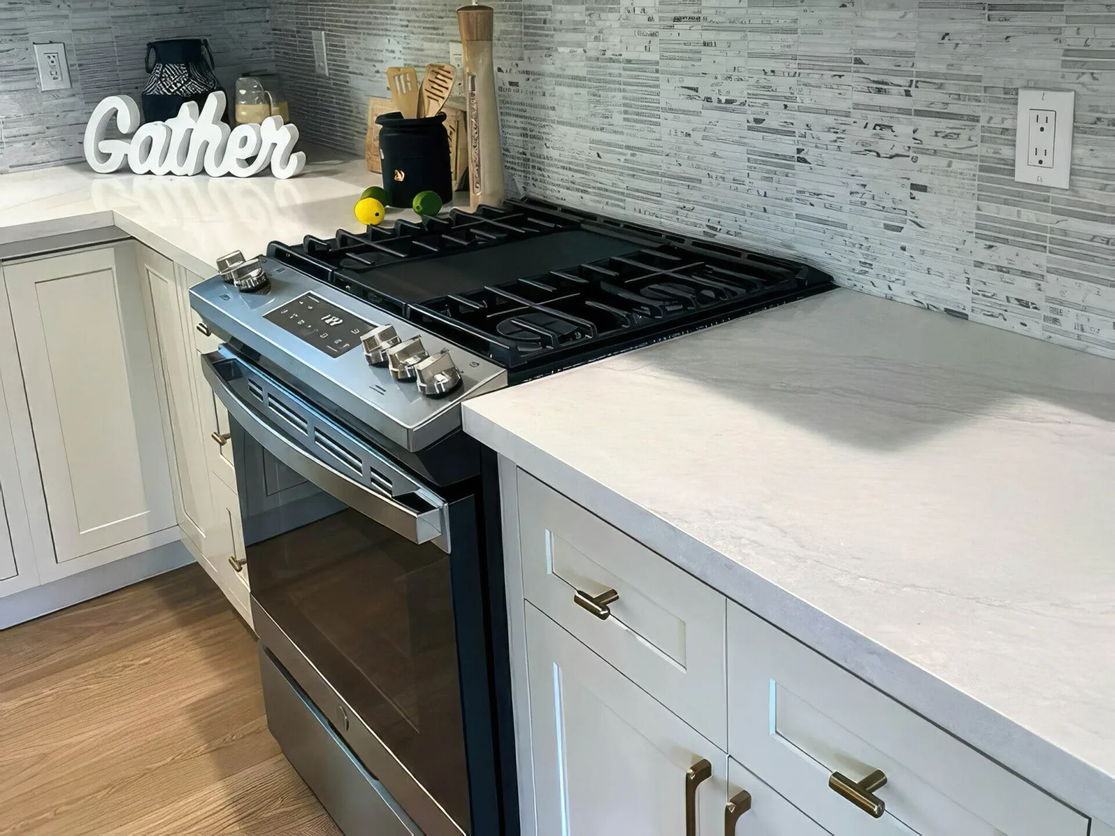 Clean kitchen in a Santa Clara home with a stainless slide-in gas range, white cabinets, and a grey mosaic tile backsplash.