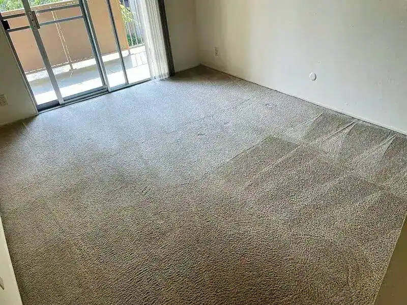 Empty bedroom with clean beige carpet and sliding glass door to balcony in Fremont.