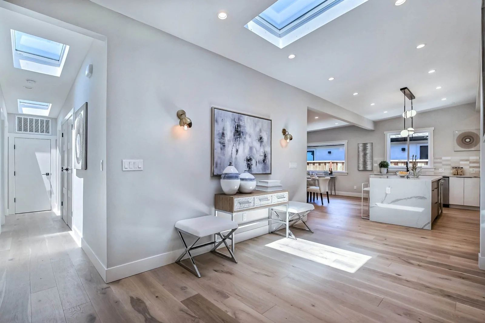 Open foyer with skylights and wood flooring leading into a modern kitchen.
