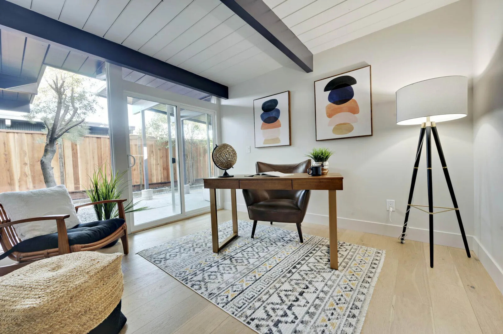 Home office with wood desk, patterned rug, and floor lamp after cleaning service.