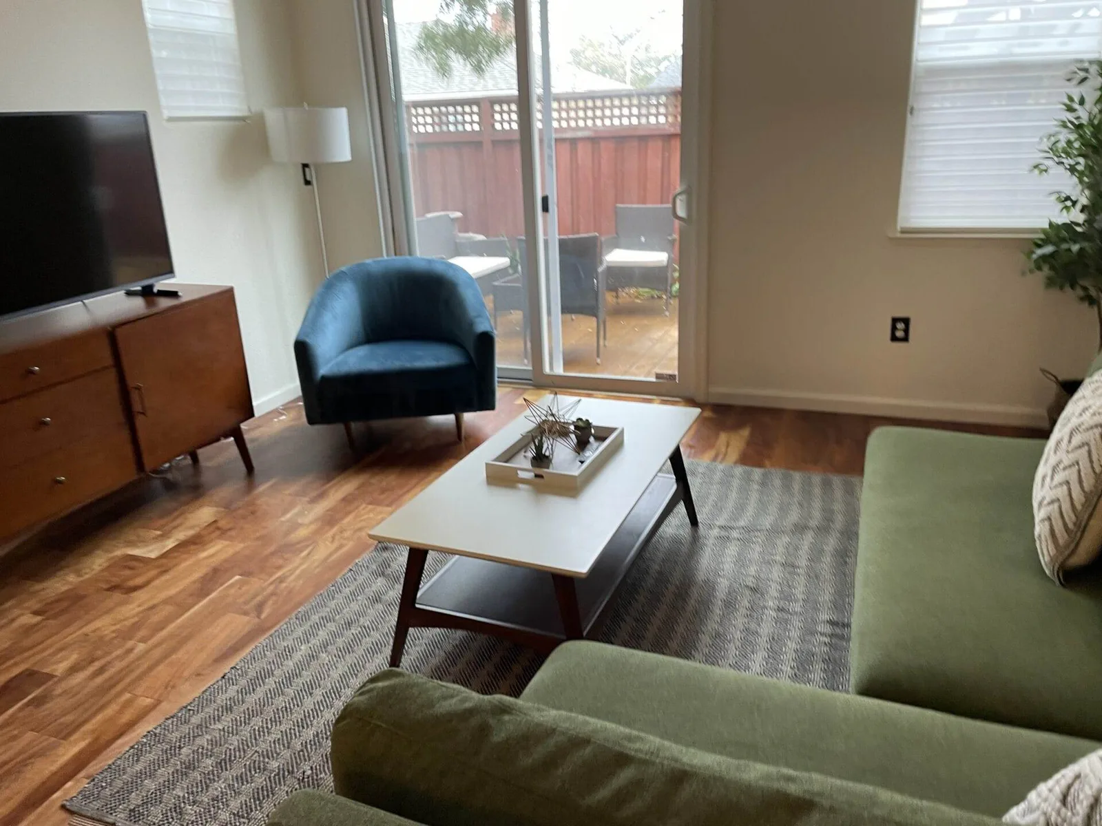 Living room with blue accent chair and wood credenza after cleaning in a San Jose home