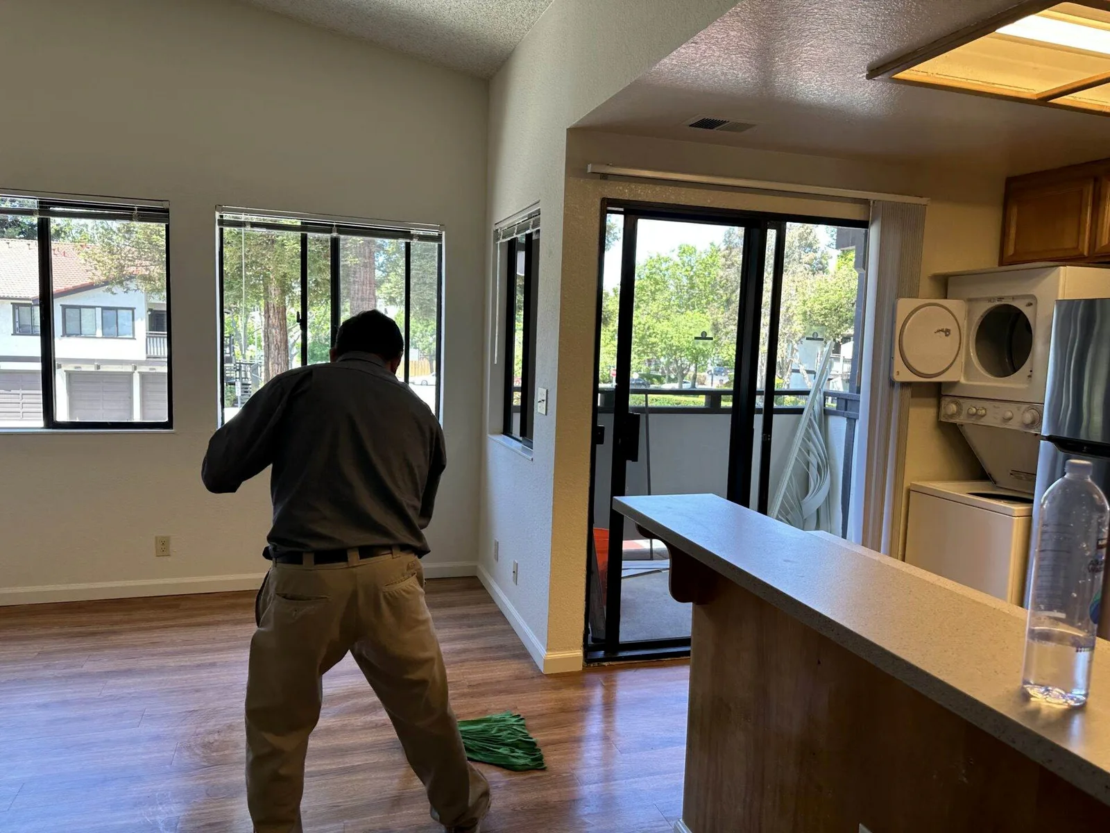 Cleaning technician walking through a living room and kitchen with a stacked washer dryer