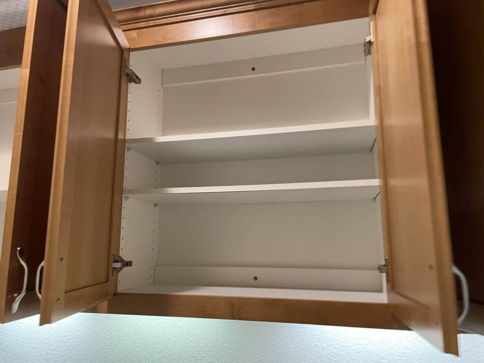 Open empty kitchen cabinet with clean white shelving in a San Jose home