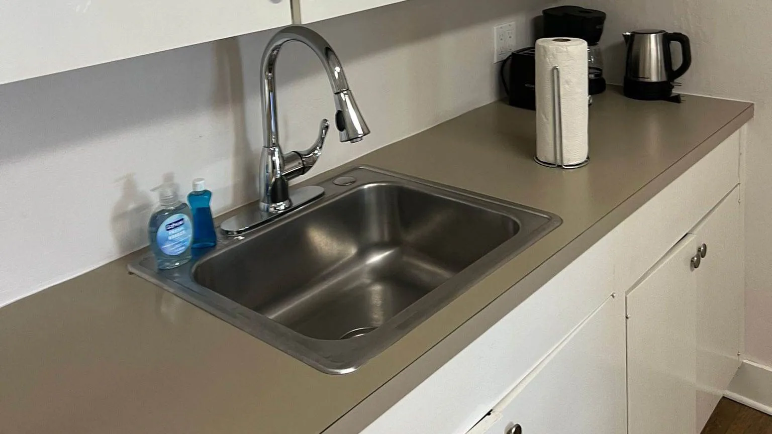 Clean stainless steel kitchen sink and countertop with soap dispensers