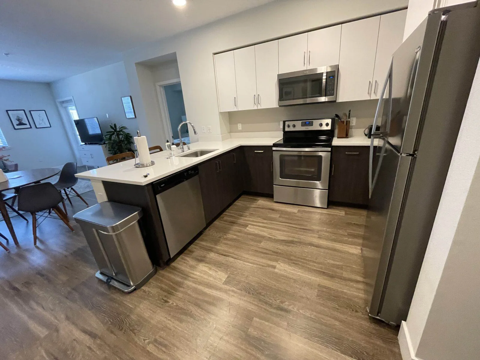 Kitchen with white cabinets, dark wood-tone lower cabinets, and stainless steel refrigerator, range, and dishwasher.
