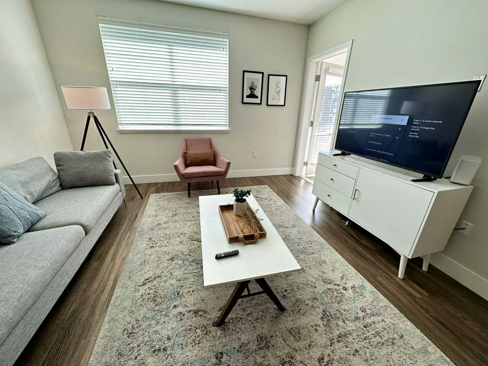 Living room with gray sofa, pink accent chair, and wall-mounted TV after allergen cleaning service.