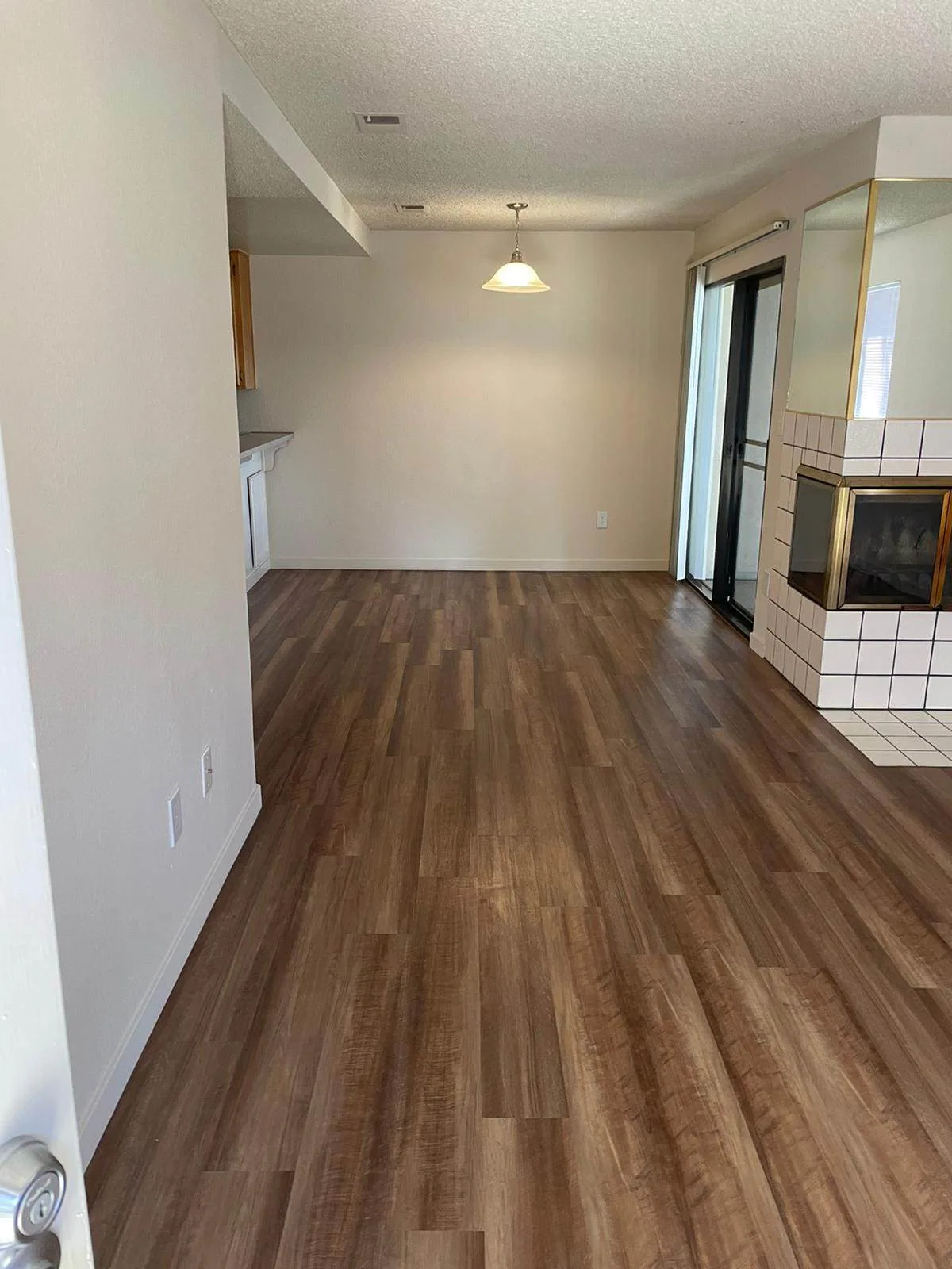 Empty living and dining area with wood-look flooring and a tile fireplace after a move-out cleaning.
