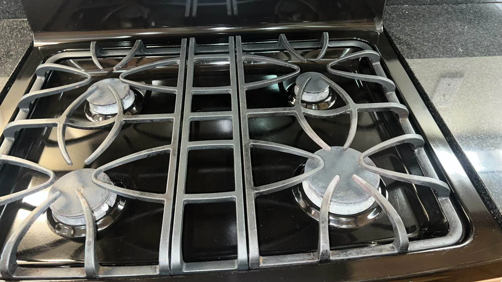 Close-up of clean cast iron stove burner grates on a granite countertop.