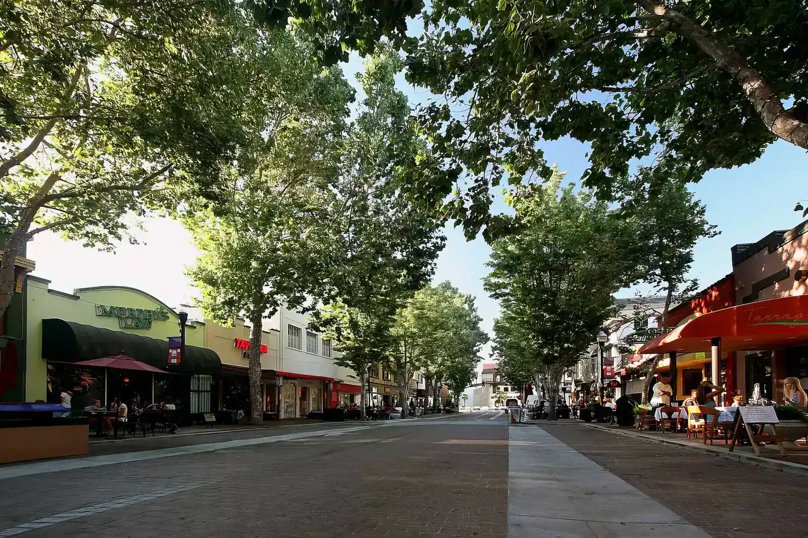 Tree-shaded pedestrian street in downtown Sunnyvale with restaurant patios on both sides.