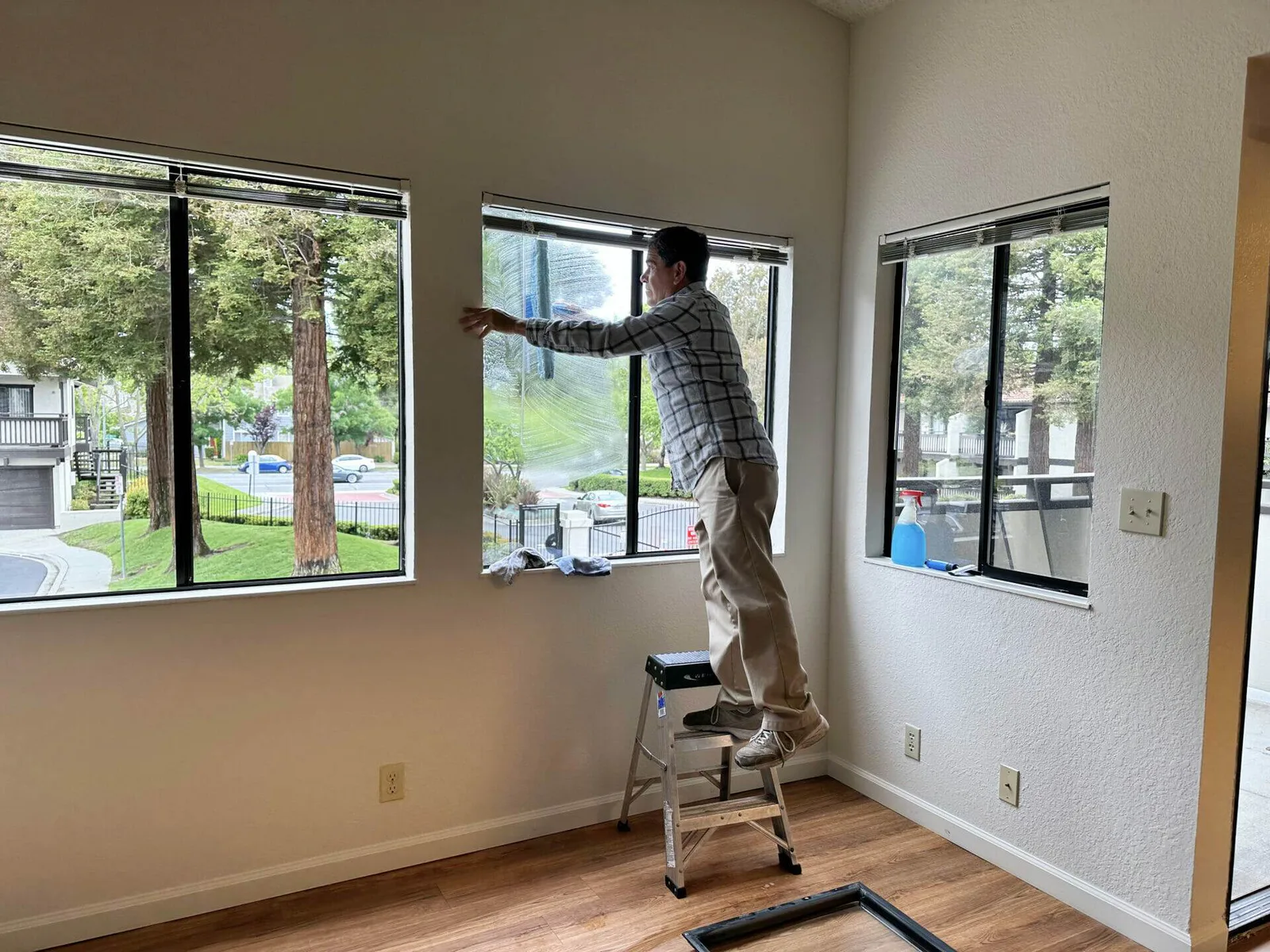 Technician wiping a window clean on a ladder, leaving a streak-free shine.