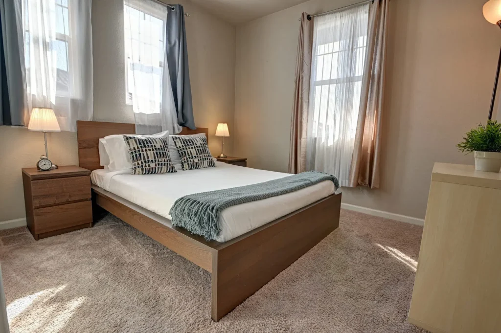 A bedroom with a bed and two windows that requires move-in or move-out cleaning in Santa Clara.