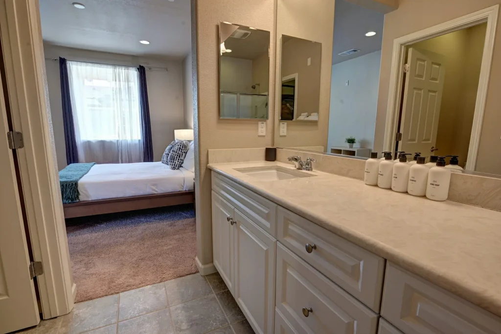 A bathroom with two sinks and a bed in need of deep cleaning.