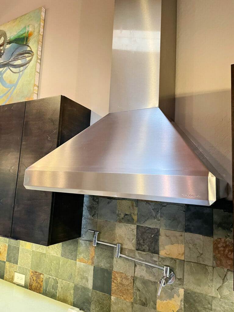 A stainless steel range hood cleaning in a kitchen.