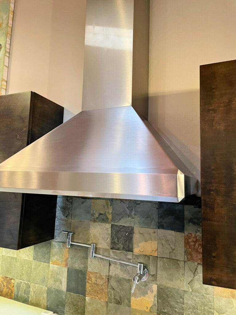 A stainless steel range hood in a kitchen that requires regular cleaning.
