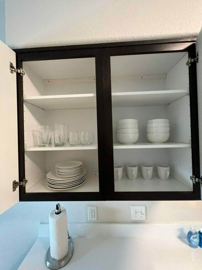 A kitchen cabinet with plates and dishes on it. (Keywords: kitchen cabinets)