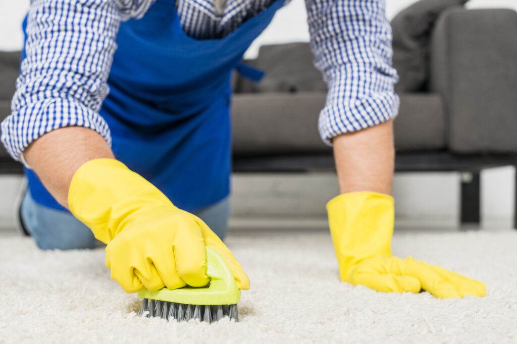 A man expertly cleaning a carpet in a living space.