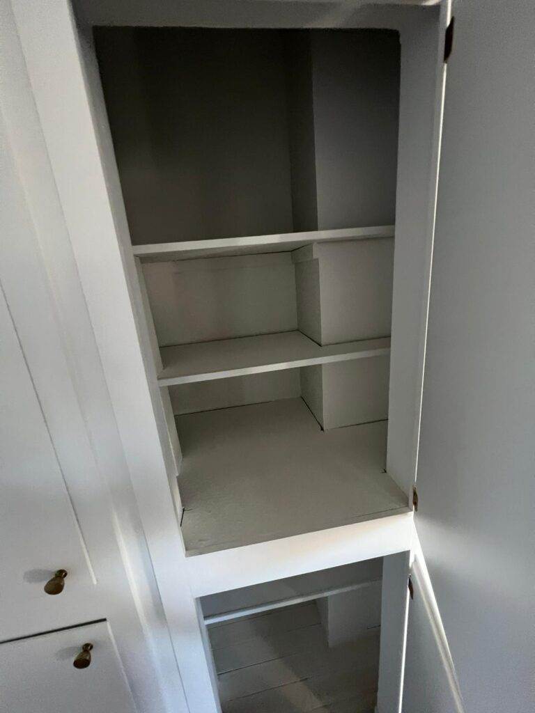 An empty white shelved closet with an open door.