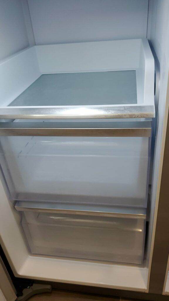 Interior of an empty refrigerator featuring two clear empty drawers and a flawless finish on a clean white shelf.