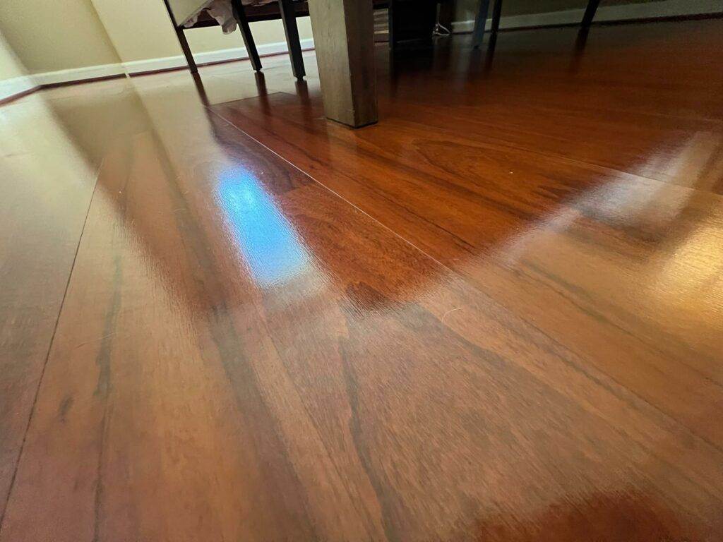 Sunlight creating a blue reflection on a polished wooden floor inside a corporate meeting room, with furniture legs visible in the background.