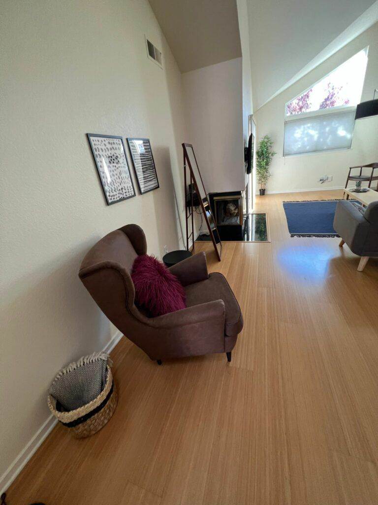 A modern living room with a revitalized brown chaise lounge, decorative ladder shelf, and framed artwork on the walls.