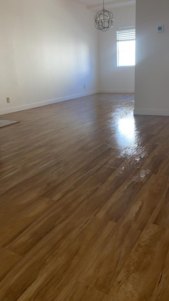 An empty room with light-colored wooden flooring, white walls, a small window, and a modern pendant light fixture hanging from the ceiling—perfect for deep cleaning ahead of flu season in Santa Clara.