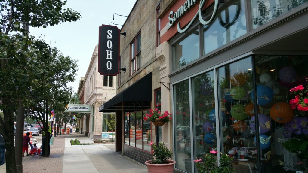 Street view of a Los Gatos sidewalk with storefronts, including a shop with a "SOHO" sign, potted flowers, and colorful decorations—perfectly business ready after professional commercial post-construction cleaning.