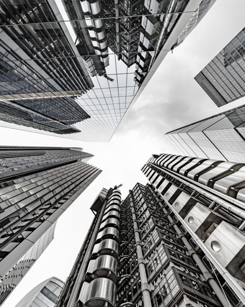 Looking up at modern skyscrapers and glass buildings from ground level in Saratoga, showcasing geometric lines and reflective surfaces against a cloudy sky—an inspiring view ideal for homeowners seeking expert post-construction cleaning.