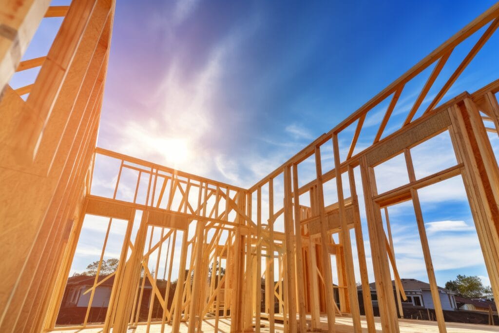 Wooden framing of a house under construction in Saratoga, with clear blue sky and sunlight in the background—ideal for post-construction cleaning before moving forward.