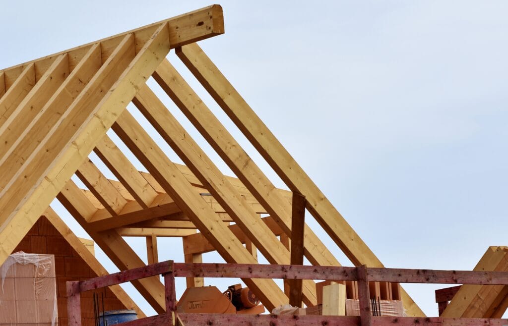 Partially constructed wooden roof frame on a building in Santa Clara County, with exposed beams and some construction materials visible in the foreground—perfect for post-renovation remodel cleaning.