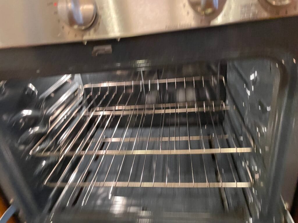 An open oven with two metal racks inside, viewed from the front. The oven control knobs are visible at the top—perfect for deep cleaning in your San Jose home.
